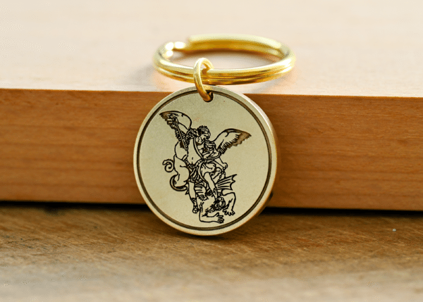 Brass keychain medallion engraved with Saint Michael the Archangel defeating a demon