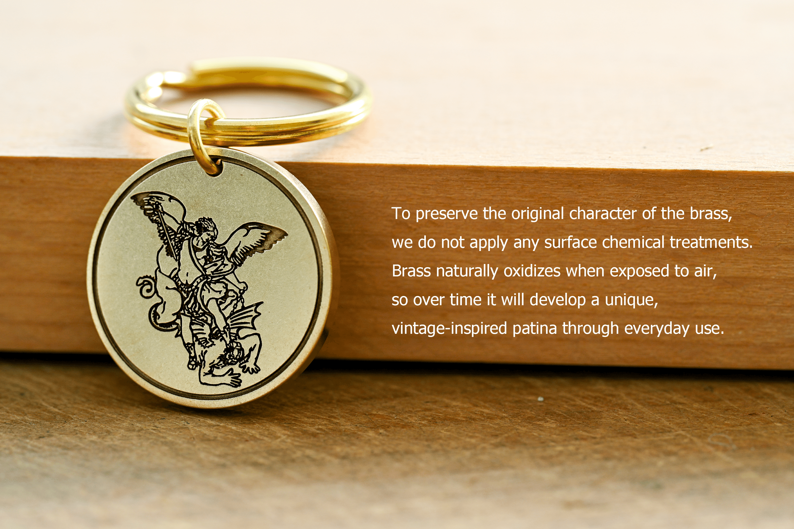 Brass keychain engraved with Archangel Michael alongside text: To preserve the original character of the brass, we do not apply any surface chemical treatments. Brass naturally oxidizes when exposed to air, so over time it will develop a unique, vintage-inspired patina through everyday use
