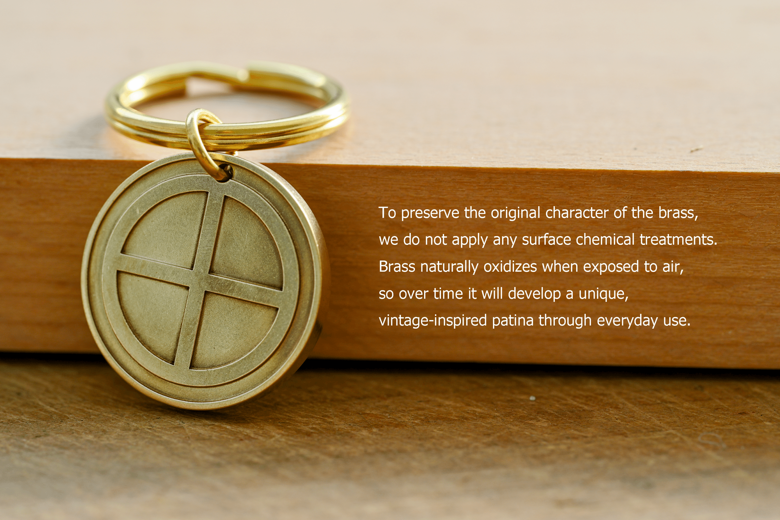 Brass sun cross keychain tag on a wooden surface with text reading: To preserve the original character of the brass, we do not apply any surface chemical treatments. Brass naturally oxidizes when exposed to air, so over time it will develop a unique, vintage-inspired patina through everyday use