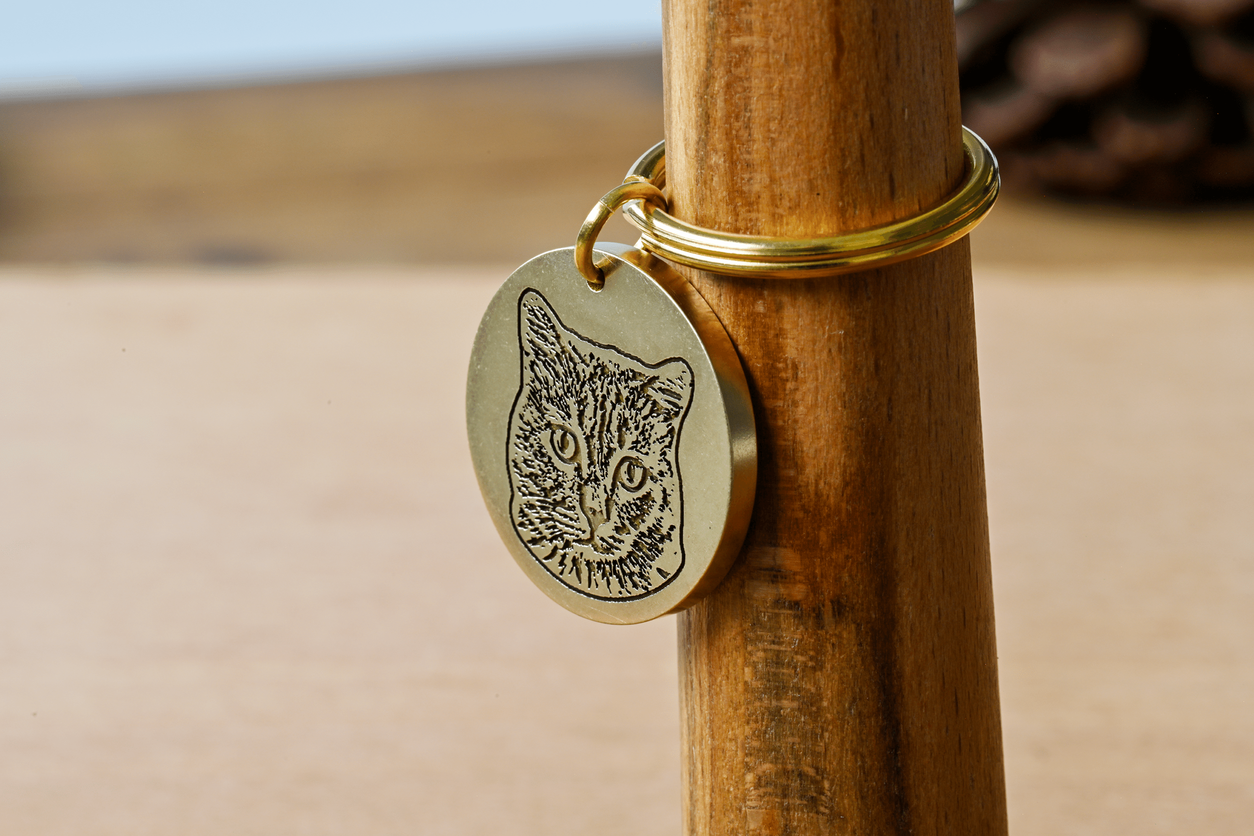Round brass tag engraved with a detailed portrait of a cat face attached to a keyring