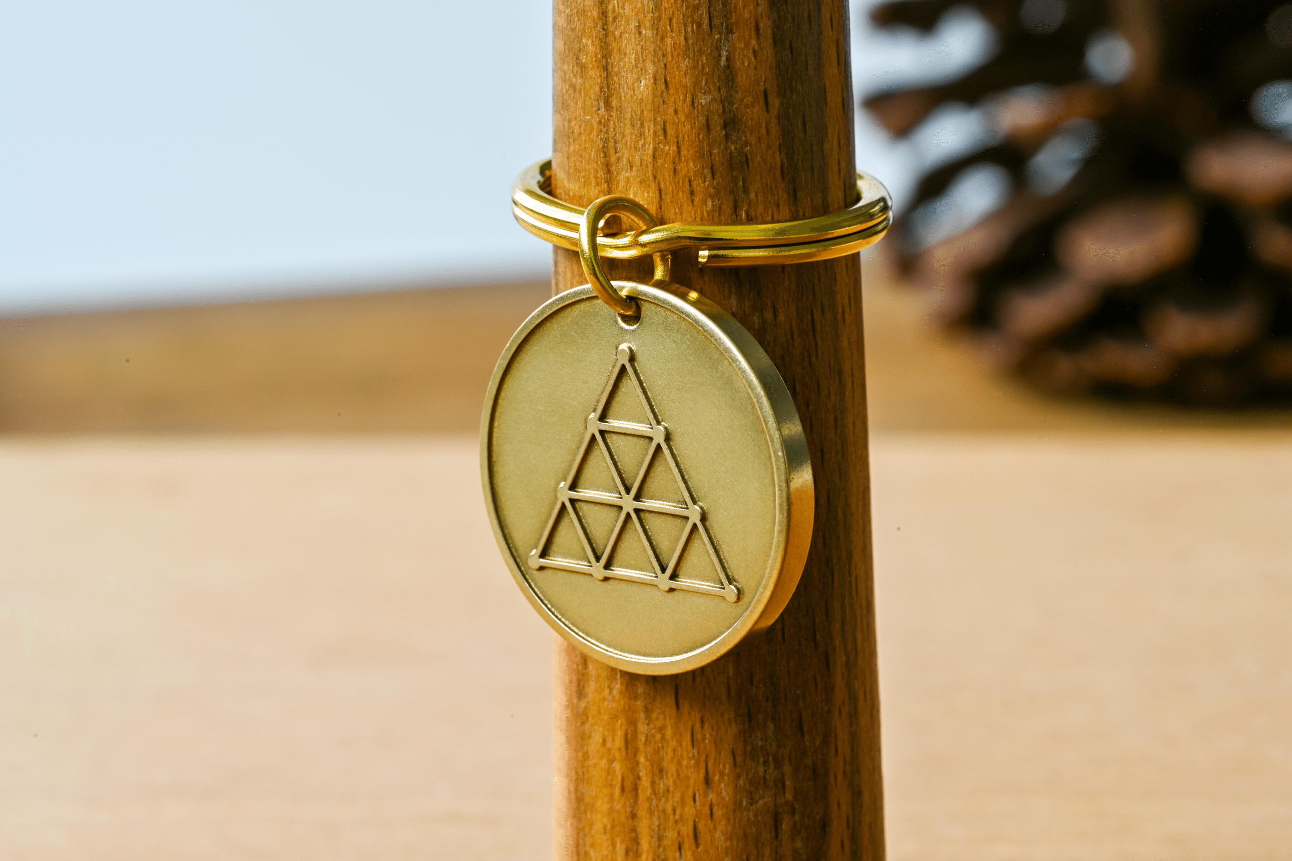 Brass circular keychain medallion engraved with a geometric triangle pattern