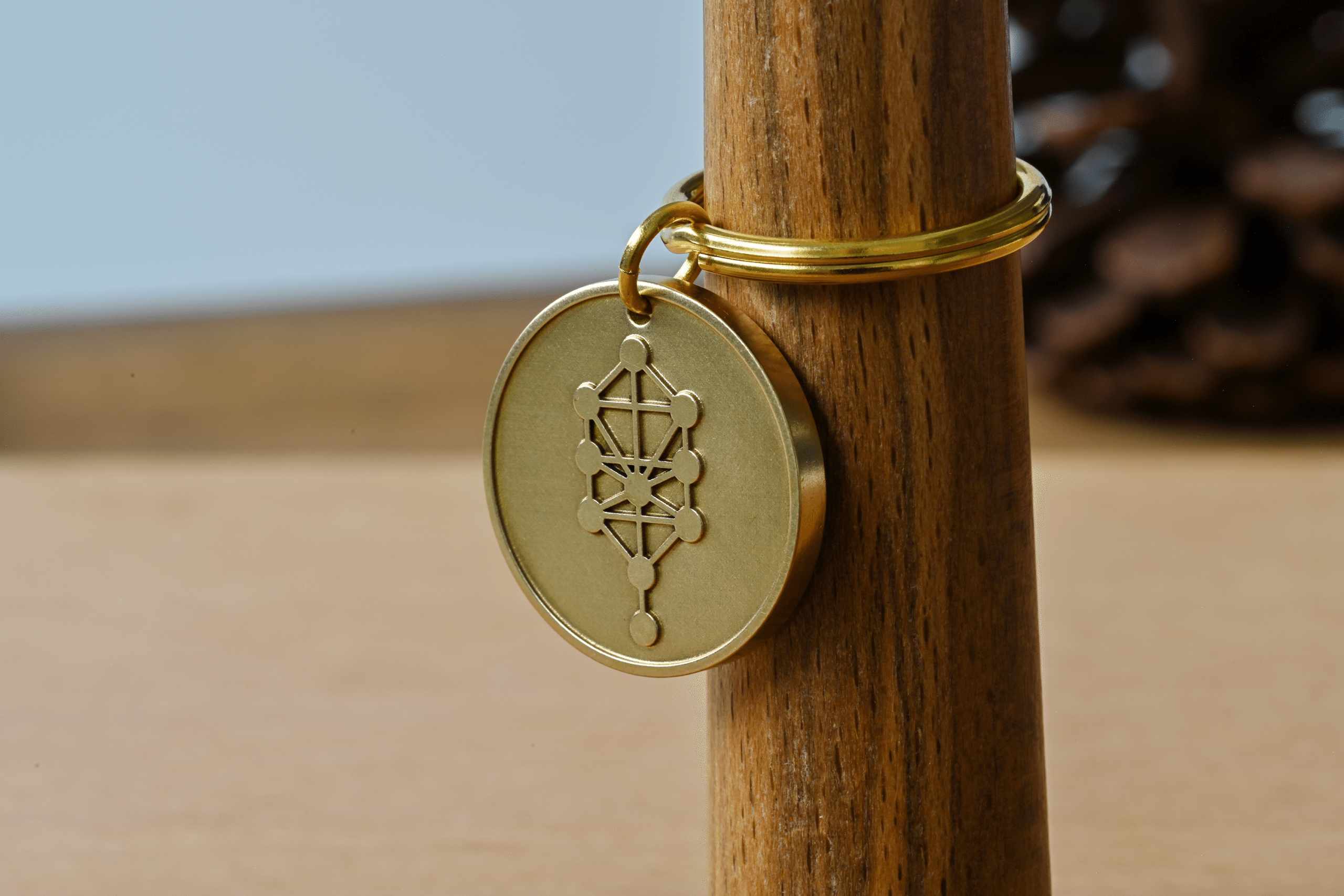 Brass keychain charm engraved with the Kabbalah Tree of Life symbol hanging on a wooden post