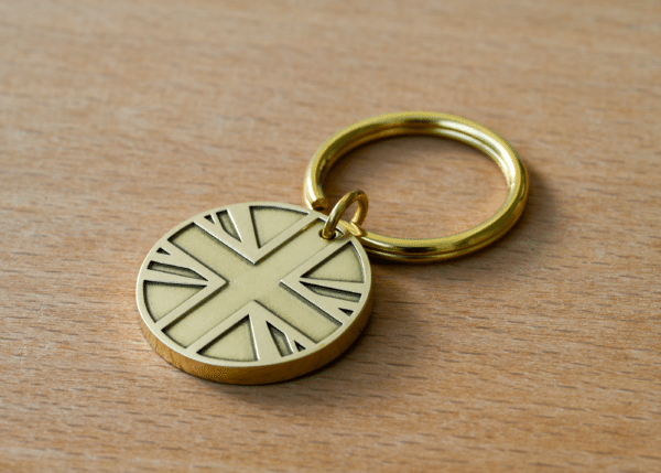 Brass keychain with a round Union Jack pendant on a wooden surface