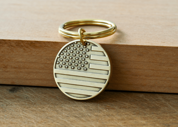 Circular brass key tag engraved with an American flag design attached to a key ring
