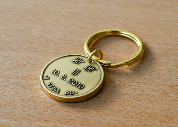 Brass keychain engraved with tally marks totaling 12, the date 10.8.2010, and the words I Still Do
