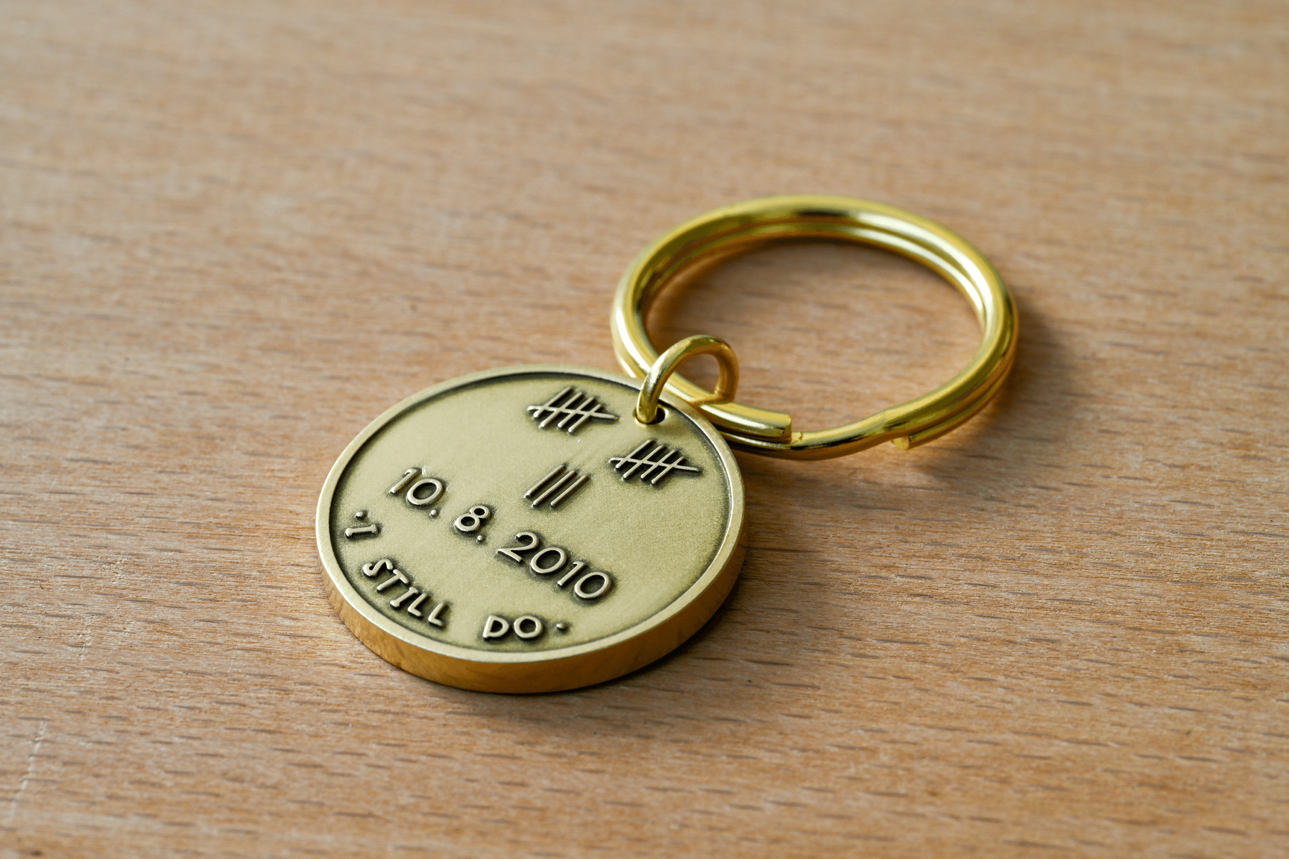 Brass keychain engraved with tally marks totaling 12, the date 10.8.2010, and the words I Still Do