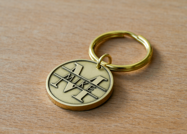 Round brass keychain tag engraved with the name MIKE inside a large monogram letter M