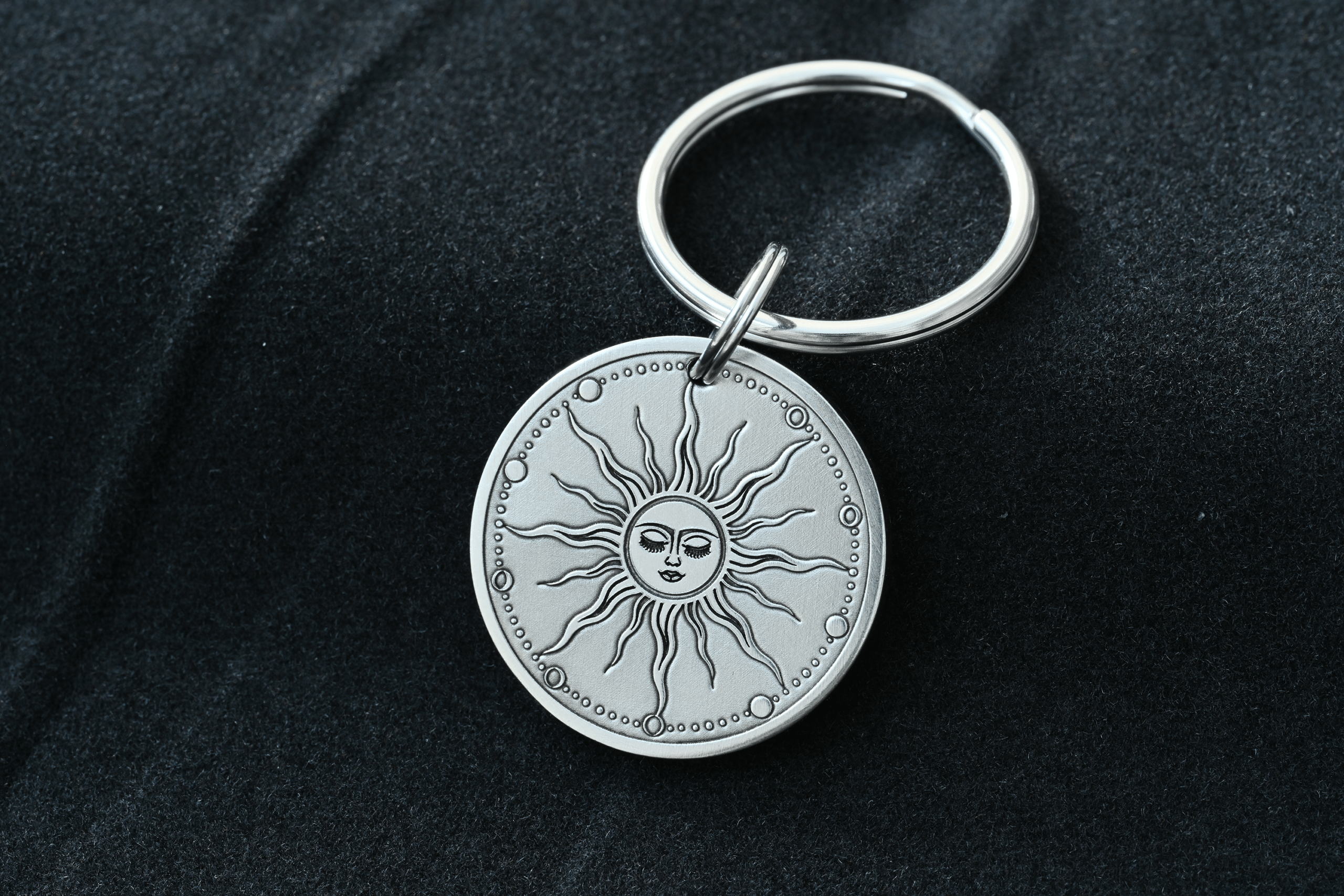 Silver round keychain engraved with a celestial sun face and radiating rays