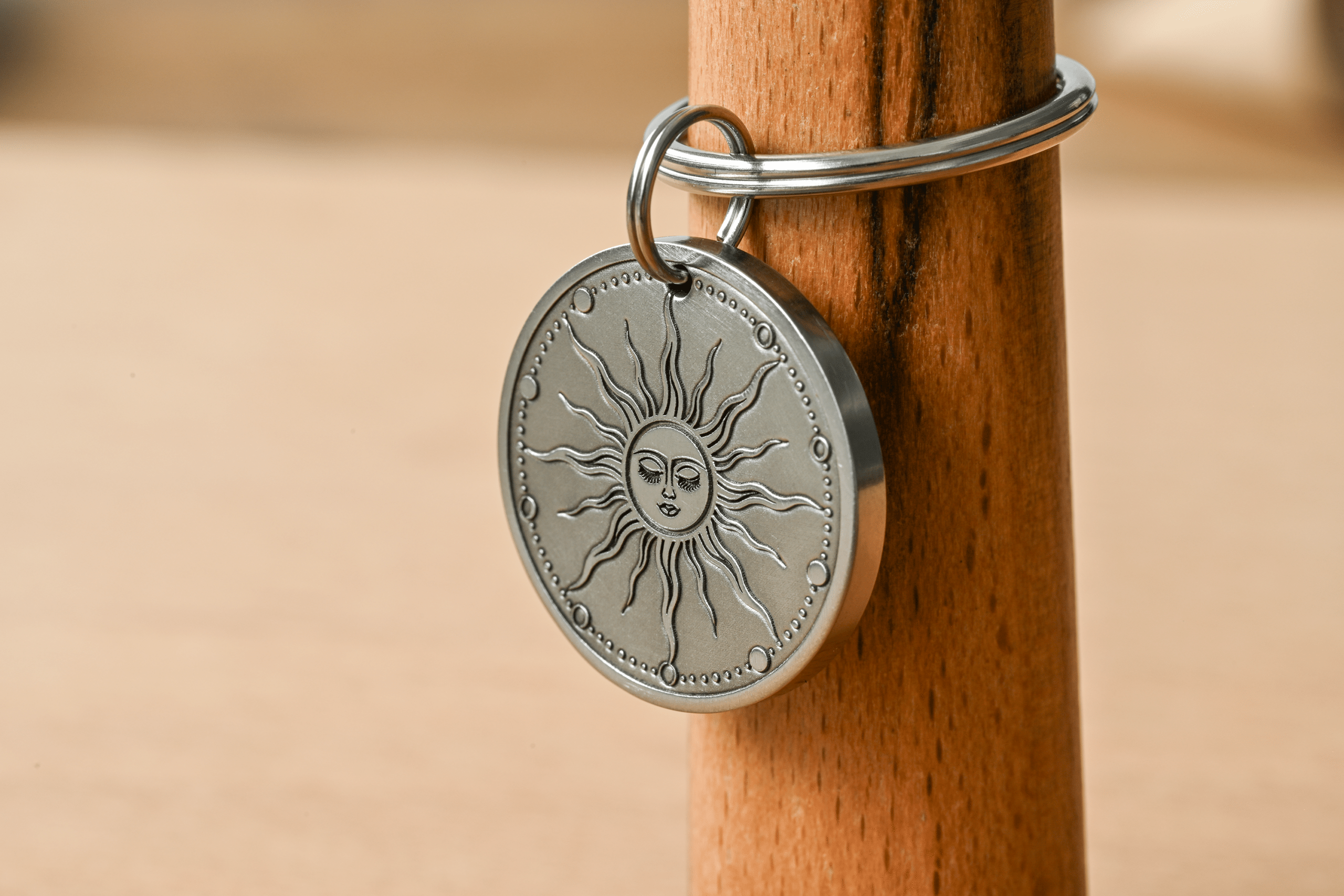 Round silver metal tag engraved with a celestial sun face and radiating rays